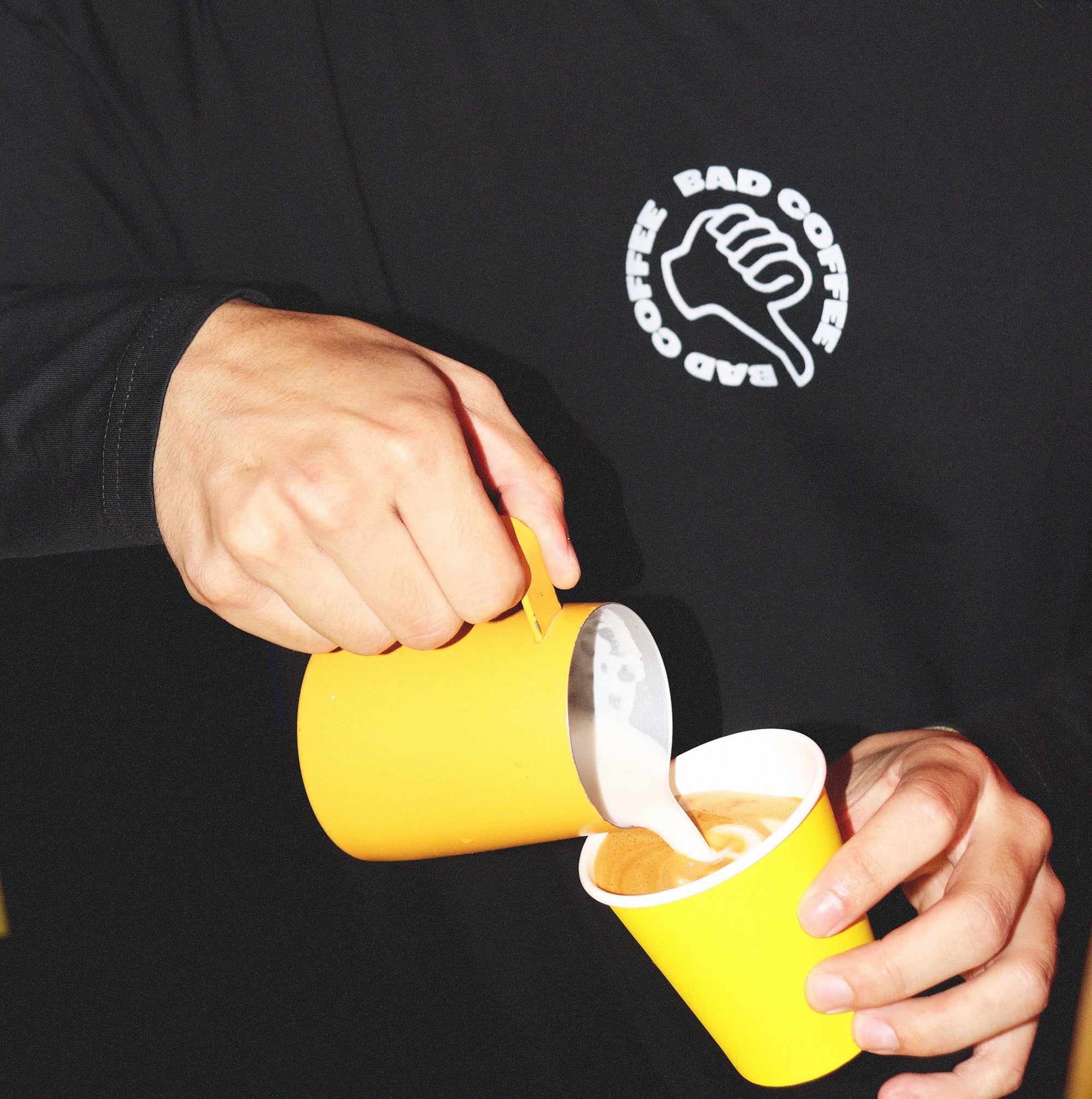 Barist pouring coffee wearing Bad Coffee T-shirt