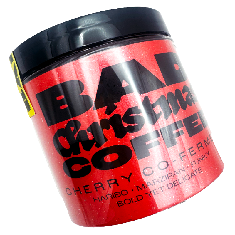 Red container with black text labeled 'Bad Christmas Coffee' Cherry Co-Ferment