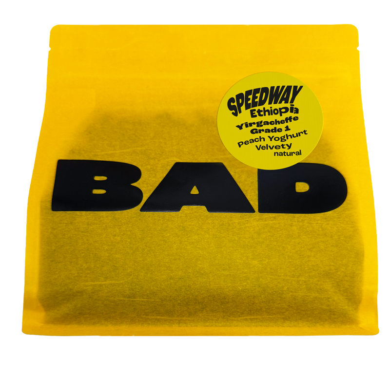 A bright yellow pouch of coffee with large black 'BAD' lettering across the front and a circular yellow label reading 'SPEEDWAY Ethiopia Yirgacheffe Grade 1, notes of Peach Yoghurt, Velvety natural'.