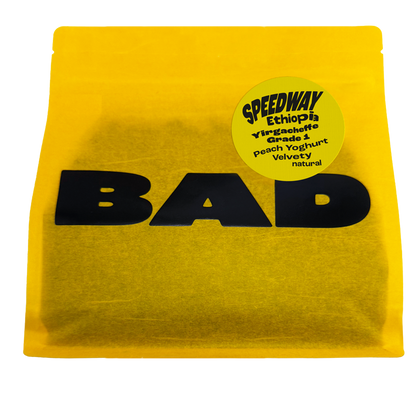 A bright yellow pouch of coffee with large black 'BAD' lettering across the front and a circular yellow label reading 'SPEEDWAY Ethiopia Yirgacheffe Grade 1, notes of Peach Yoghurt, Velvety natural'.