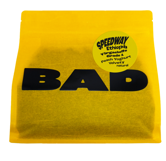 A bright yellow pouch of coffee with large black 'BAD' lettering across the front and a circular yellow label reading 'SPEEDWAY Ethiopia Yirgacheffe Grade 1, notes of Peach Yoghurt, Velvety natural'.